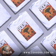 Футболка вибуховий арт BOOM білого кольору, зображена на манекені, фон світло-сірий, принт з ядерним вибухом та скелетами в червоних та оранжевих тонах.