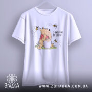 Футболка з любовʼю до бджіл, білого кольору, підвішена на вішалці, фон нейтральний, принт з ведмедиком, що тримає банку з медом, оточений бджолами.