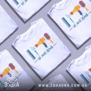 Футболка зброя перукаря, біла, зображена на манекені, фон світло-сірий, принт містить гребінець, ножиці, фен та щітку, виконаний у яскравих кольорах.