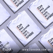 Футболка жарт про майстрів, біла, зображена з фронтального ракурсу, фон нейтральний, принт містить текст "Сім раз відміряй один хукриво" та малюнок персонажа, що тримає руки в боки, поряд лінійка.