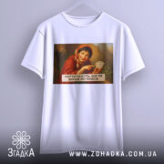 Футболка жартівлива гадалка, біла, підвішена на вішалці, фон світло-сірий, принт з жінкою в червоному шарфі, яка тримає карти, текст на принті чорний, розташований під зображенням.