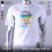 Футболка жіночий образ України, біла, зображена з фронтального ракурсу, фон світло-сірий, принт з малюнком дівчини з косою та кольоровими смугами синього і жовтого кольору, текст 'Ukraine' під малюнком.