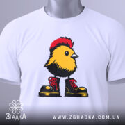 Футболка Жовта пташка, складена футболка з принтом жовтої пташки в червоних черевиках, фон світло-сірий, на футболці видно етикетку з логотипом.