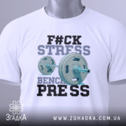 Футболка жим замість стресу, біла, складена на столі, фон світло-сірий, принт з написом 'F#CK STRESS' та зображенням гантелі, виконаний у блакитних та чорних кольорах, з етикеткою на зеленому шнурку.