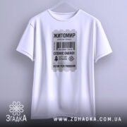 Футболка Житомир білого кольору, підвішена на вішалці, фон світло-сірий, принт у вигляді квитка з текстом 'Житомир', 'COSMIC ENERGY', 'SCAN FOR FREEDOM' у чорному кольорі, видно округлі краї рукавів.
