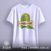 Футболка злюкозавр сердитий, біла, зображена на вішалці, фон світло-сірий, принт злюкозавра з зеленим тілом, тримає табличку з написом 'ЗЛЮКОЗАВР'.