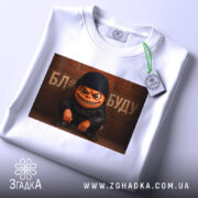 Футболка злий персонаж, біла, зображена зверху, фон світлий, принт з злим персонажем у чорній шапці та куртці, текст на фоні, з етикеткою.