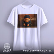 Футболка злий персонаж, біла, підвішена на вішалці, фон світлий, принт з злим персонажем у чорній шапці та куртці, текст на фоні.