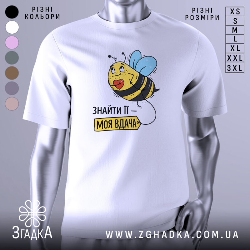 Футболка знайти її вдача, біла, зображена на манекені, фон світло-сірий, принт з бджолою з блакитними крилами та написом 'ЗНАЙТИ ЇЇ – МОЯ ВДАЧА'.