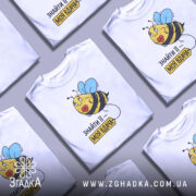 Футболка знайти її вдача, біла, зображена на манекені, фон світло-сірий, принт з бджолою з блакитними крилами та написом 'ЗНАЙТИ ЇЇ – МОЯ ВДАЧА'.