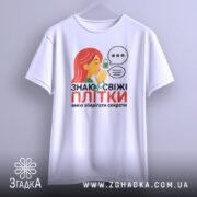 Футболка Знаю свіжі плітки білого кольору, зображена на манекені, фон світло-сірий, принт з дівчиною з червоним волоссям, що шепоче, з елементами замка та діалогових вікон.