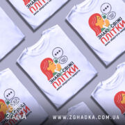 Футболка Знаю свіжі плітки білого кольору, зображена на манекені, фон світло-сірий, принт з дівчиною з червоним волоссям, що шепоче, з елементами замка та діалогових вікон.