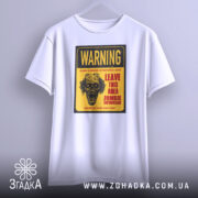Футболка зомбі попередження, біла, підвішена на вішалці, фон світло-сірий, принт з черепом та текстом жовтого кольору.