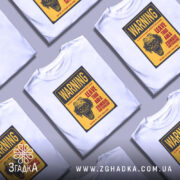 Футболка зомбі попередження, біла, зображена на манекені, фон нейтральний, принт з черепом та текстом жовтого кольору.