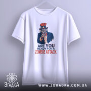 Футболка zombie attack білого кольору, підвішена на вішалці, фон світло-сірий, принт з черепом у капелюсі зірки та написом 'ARE YOU READY FOR A ZOMBIE ATTACK' у червоному та синьому кольорах.