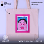 Шопер для класних бежевий, з прямим ракурсом, на фоні світлого градієнту, з тонкої бавовняної тканини, довжина ручок середня, місткість достатня для повсякденних речей, принт з написом 'I am cool' на яскравому рожевому фоні.