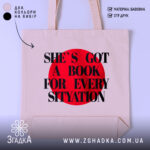 Шопер для книгоманів бежевий з червоним принтом на фоні студійного світла