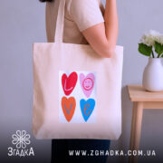 Шопер для закоханих. Бежевий, зображення спереду, на нейтральному фоні. Тканина середньої товщини, ручки середньої довжини, місткість достатня для повсякденних речей, принт з серцями та написом 'LOVE' у яскравих кольорах.