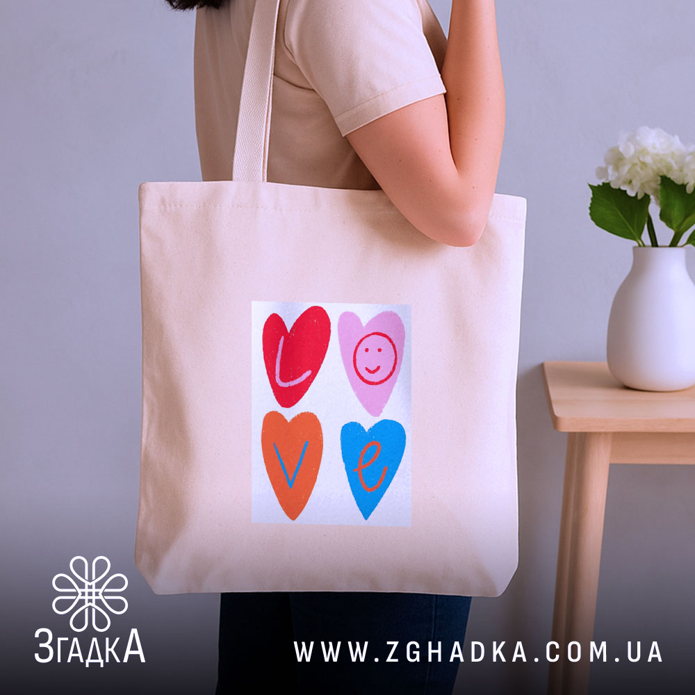 Шопер для закоханих. Бежевий, зображення спереду, на нейтральному фоні. Тканина середньої товщини, ручки середньої довжини, місткість достатня для повсякденних речей, принт з серцями та написом 'LOVE' у яскравих кольорах.