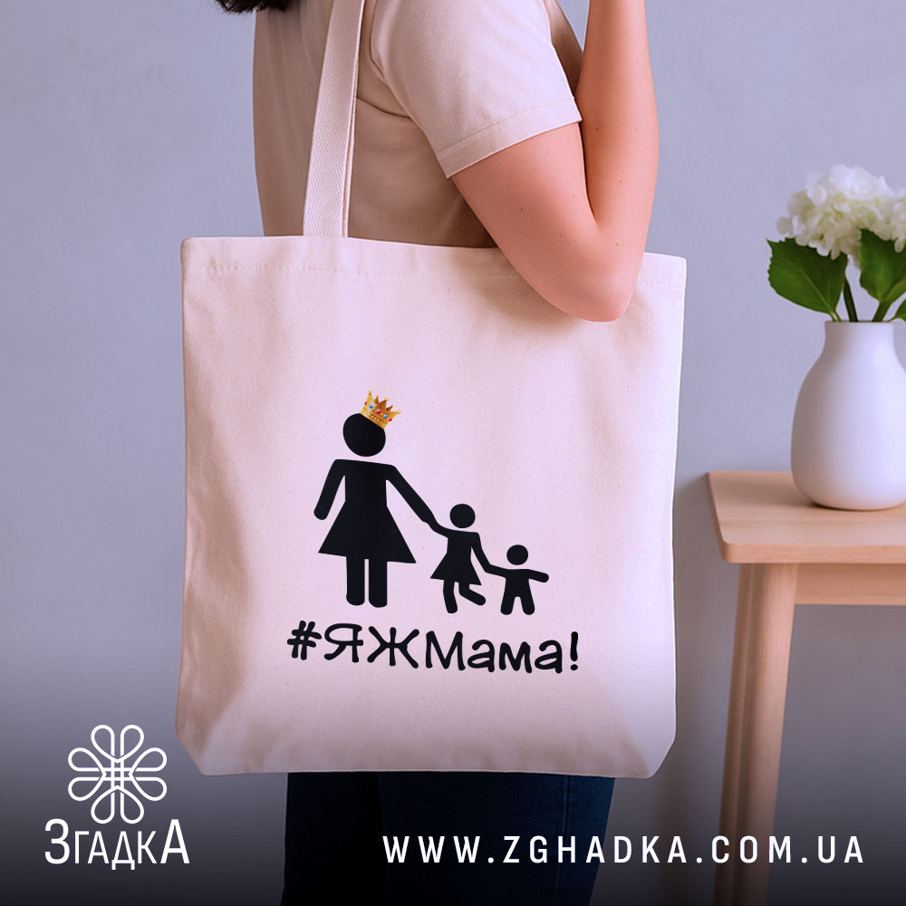 Шопер яжмама, бежевий, з боку, на нейтральному фоні, тонка бавовняна тканина, довгі ручки, місткий, принт з жінкою в сукні та двома дітьми, напис #ЯЖМама!