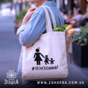 Шопер яжмама, бежевий, з боку, на вуличному фоні, тонка бавовняна тканина, довгі ручки, місткий, принт з жінкою в сукні та двома дітьми, напис #ЯЖМама!