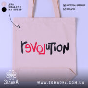 Шопер любовна революція, бежевого кольору, зображений з близької відстані, на світлому фоні, виготовлений з тонкої бавовняної тканини, ручки середньої довжини, місткий, з принтом 'revoluTion' у червоному та чорному кольорах.