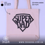 Шопер супер тато — шопер на манекені, вид спереду з чітким принтом.