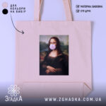 Шопер жартівлива Мона Ліза, бежевий, з фронтального ракурсу, на нейтральному фоні, з тонкої бавовняної тканини, з короткими ручками, місткий, з принтом класичної картини Мона Ліза з жувальною гумкою в роті.