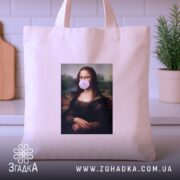 Шопер жартівлива Мона Ліза, бежевий, з заднього ракурсу, на кухонному фоні, з тонкої бавовняної тканини, з короткими ручками, місткий, з принтом класичної картини Мона Ліза з жувальною гумкою в роті.