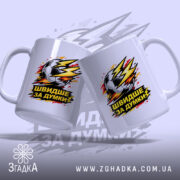 Чашка для футболіста, біла, з ракурсом спереду, на фоні світло-фіолетового кольору, з двома принтами футбольного м'яча та написом 'ШВИДШЕ ЗА ДУМКИ', ручки класичні, край рівний, глянцевий.