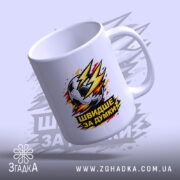 Чашка для футболіста, біла, з ракурсом спереду, на фоні світло-фіолетового кольору, з принтом футбольного м'яча та написом 'ШВИДШЕ ЗА ДУМКИ', ручка класична, край рівний, глянцевий.