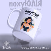 Чашка для щасливої Юлі. Біла чашка з глянцевим покриттям, зображення дівчини з коктейлем на передній стороні. Ручка круглої форми, край чашки рівний. Фон ніжно-фіолетовий, текст чорного кольору з веселим шрифтом.