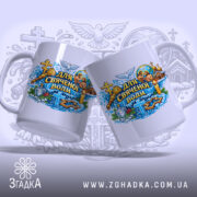 Чашка для свяченої води, білого кольору, з кольоровим принтом, що показує різні релігійні символи, ручки дві, одна з чашок повернена до камери, край рівний, глянцева поверхня, фон з розмитими елементами.