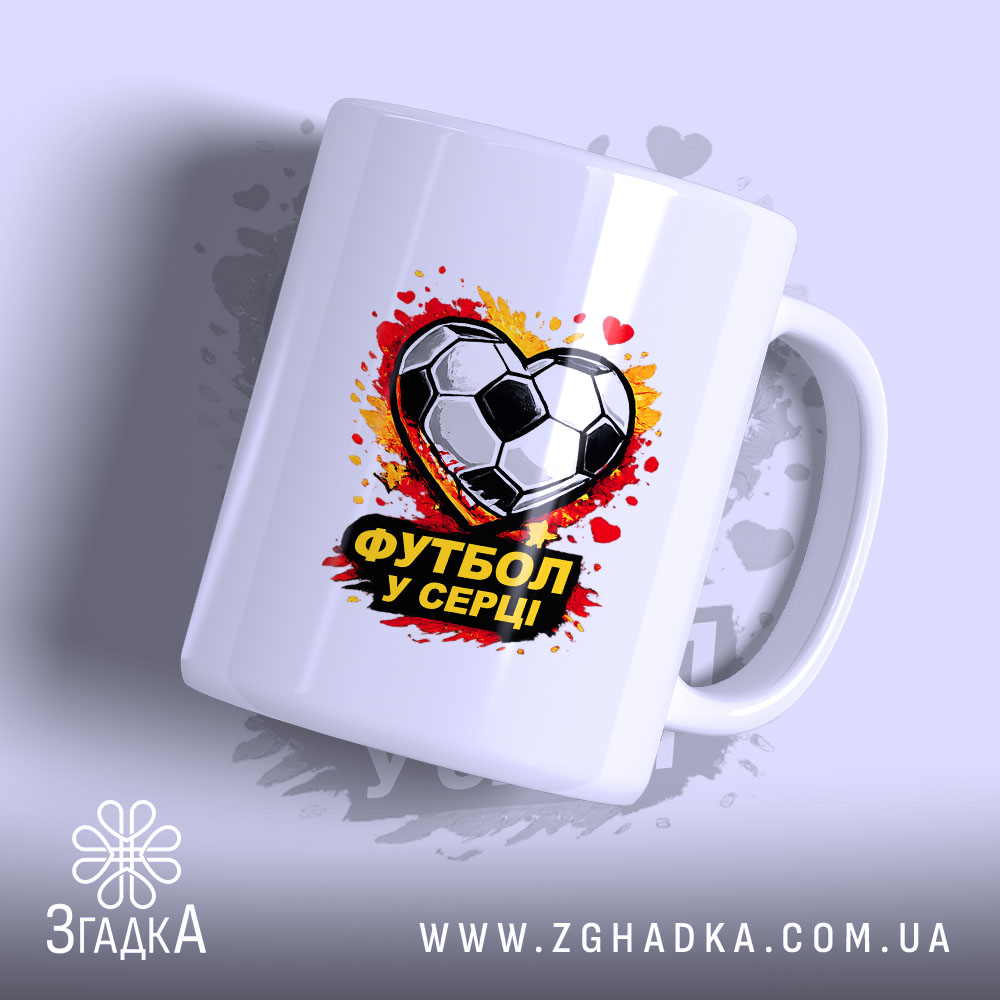 Чашка Футбол у серці, біла, з зображенням футбольного м'яча у формі серця, на фоні червоних і жовтих плям, ручка стандартна, край рівний, глянцева поверхня.