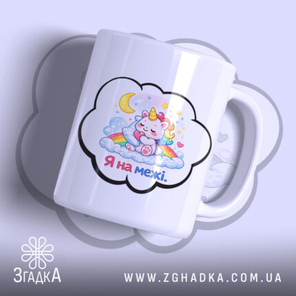 Чашка Я на межі. Біла чашка з малюнком єдинорога, який спить на хмарах, з веселкою та зірками. Ручка чашки гладка, край рівний, поверхня глянцева. Фон ніжно-фіолетовий.