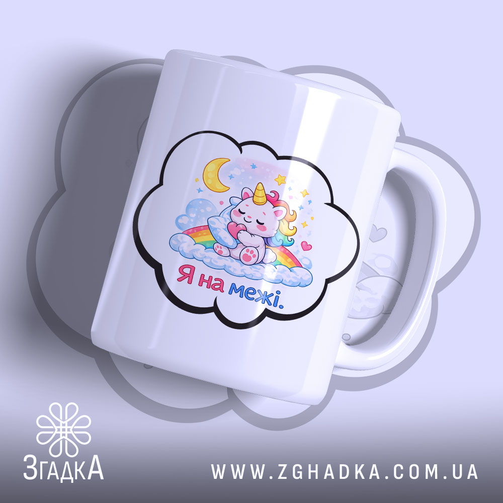 Чашка Я на межі. Біла чашка з малюнком єдинорога, який спить на хмарах, з веселкою та зірками. Ручка чашки гладка, край рівний, поверхня глянцева. Фон ніжно-фіолетовий.