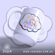 Чашка Я на межі. Біла чашка з малюнком єдинорога, що спить на хмарах, з веселкою та зірками, зображена під кутом. Ручка гладка, край рівний, поверхня глянцева. Фон ніжно-фіолетовий.