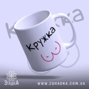 Чашка ЇЇ кружка білого кольору з чорним написом 'КРУЖКА' та малюнком у вигляді грудей рожевого кольору, ракурс спереду, фон світло-фіолетовий, глянцева поверхня, круглий край, зручна ручка.