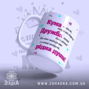 Чашка її величність Кума має білий колір з яскравим принтом, нахилена під кутом. На ній видно текст про дружбу. Ручка гладка, край рівний. Поверхня матова, фон ніжно-фіолетовий з елементами принта у вигляді сердечок і зірочок.