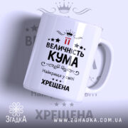 Чашка хрещеній на подарунок, біла з чорним принтом, зображена під кутом, фон світло-сірий, на передній частині напис "ВЕЛИЧНІСТЬ КУМА" з червоними акцентами, ручка класична, край рівний, глянцева поверхня.