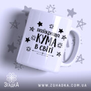 Чашка найкращої куми білого кольору з чорним написом "найкраща КУМА в світі" та зірочками на фоні, ручка гладка, край рівний, поверхня глянцева.