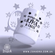 Чашка найкращої куми білого кольору з чорним написом "найкраща КУМА в світі" та зірочками на фоні, ручка гладка, край рівний, поверхня глянцева, вид з боку.