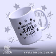 Чашка найкращої куми білого кольору з чорним написом "найкраща КУМА в світі" та зірочками на фоні, ручка гладка, край рівний, поверхня глянцева, вид зверху.