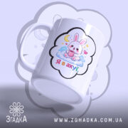 Чашка подарунок з зайчиком, біла з кольоровим принтом, зображення зайчика на хмарі з чашкою, напис 'Я в ахуї' під зайчиком, ручка класична, край рівний, глянцева поверхня.
