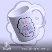 Чашка подарунок з зайчиком, біла з кольоровим принтом, зображення зайчика на хмарі з чашкою, напис 'Я в ахуї' під зайчиком, ручка класична, край рівний, глянцева поверхня.