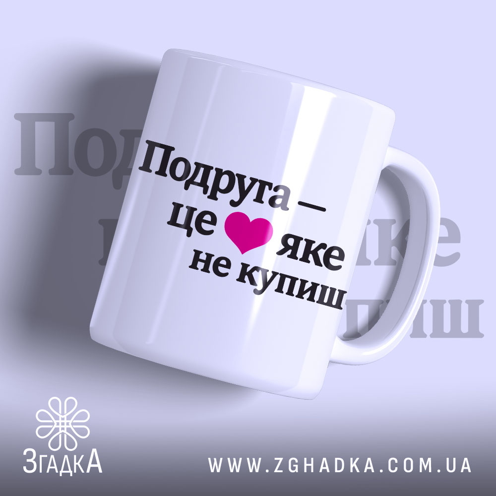 Чашка про дружбу подрузі, біла, з ракурсом спереду, на фоні світло-фіолетового кольору, з чорним написом "Подруга – це ❤️ яке не купиш", ручка круглої форми, край рівний, глянцева поверхня.