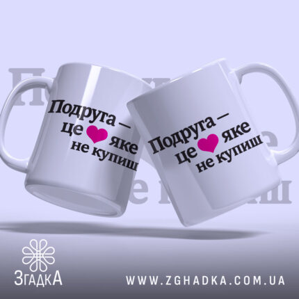 Чашка про дружбу подрузі, дві білих чашки, з ракурсом зліва, на фоні світло-фіолетового кольору, з чорним написом "Подруга – це ❤️ яке не купиш", ручки круглої форми, краї рівні, глянцева поверхня.