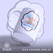 Чашка прикол мені всеодно біла, з зображенням цуценяти, що тримає повітряну кулю, з боку ручки. Принт оточений хмаринкою, на якій написано 'Менi похуй'. Ручка гладка, край рівний, поверхня глянцева.