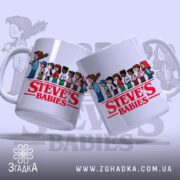 Чашка Steve's Babies показує два ракурси, один з яких зосереджений на червоному написі 'STEVE'S BABIES' та малюнках дітей. Чашки розташовані близько одна до одної, фон білий з легким глянцем. Ручки чашок гладкі, краї рівні.