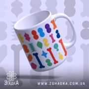Чашка цікава геометрична, біла з кольоровими принтами, зображена під кутом, фон світло-сірий, ручка стандартна, край рівний, глянцева поверхня.